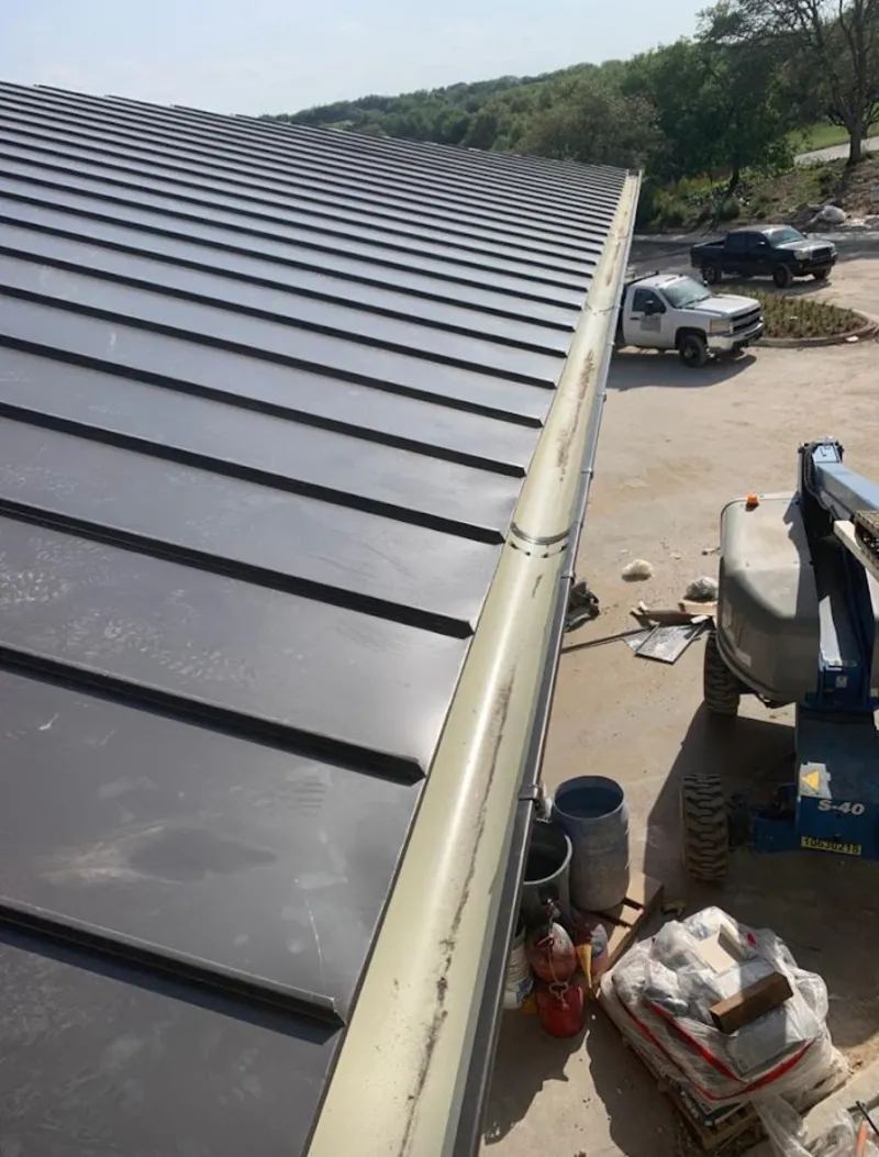 Standing seam panel and gutter detail on a metal roofing jobsite in Farmington